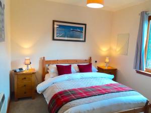 ein Schlafzimmer mit einem Bett mit zwei Nachttischen und zwei Lampen in der Unterkunft Loch Ness Highland Cottages with partial Loch View in Invermoriston