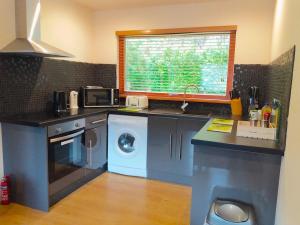 eine Küche mit Spüle und Waschmaschine in der Unterkunft Loch Ness Highland Cottages with partial Loch View in Invermoriston