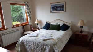 a bedroom with a bed with blue and green pillows at Lochview Guest House in Ullapool