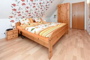 Schlafzimmer mit einem Holzbett mit Blumentapete in der Unterkunft haus-sand-am-meer in Neuharlingersiel