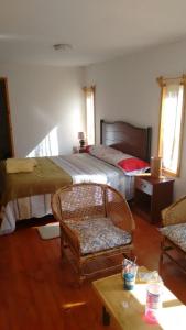 a bedroom with two beds and a chair and a table at cabañas sector peñuelas in Coquimbo +2 photos
