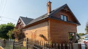 uma casa de madeira com uma cerca em frente em Pokoje Gościnne Nad Wkra em Joniec