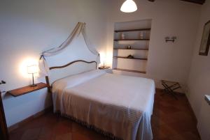 1 dormitorio con 1 cama con colcha blanca en Agriturismo Villa Opera, en Volterra
