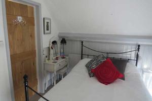 長梅爾福德的住宿－St.Catherine`s Cottage, The Old School House，一间卧室配有一张带红色枕头的床和一张书桌