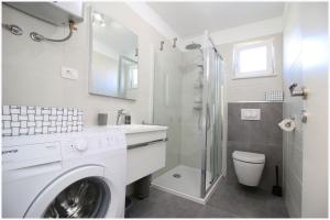 a white bathroom with a washing machine and a toilet at Apartments Silver Beauty in Rogoznica +17 photos