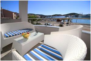 a balcony with two chairs and a table with a bowl of fruit at Apartments Silver Beauty in Rogoznica