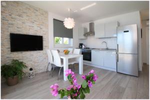 a kitchen with a white table and a white refrigerator at Apartments Silver Beauty in Rogoznica