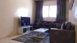 a living room with a couch and a tv at Suite Apartment Fawzi in Agadir