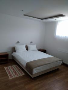 a bedroom with a bed with white sheets and a window at Simića ćoše in Vrdnik