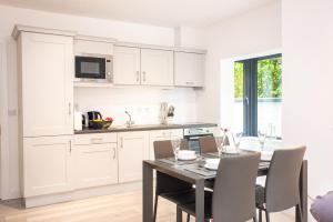 una cocina con armarios blancos y una mesa con sillas. en Kinvara House, en Killarney