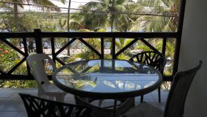 y balcón con mesa de cristal y sillas. en Praia do Forte Luxuoso Village en Mata de São João