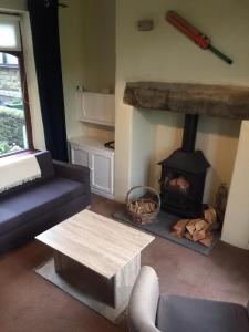 a living room with a couch and a fireplace at Wicket Green Cottage in Hayfield