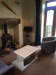 a living room with a table and a fireplace at Wicket Green Cottage in Hayfield