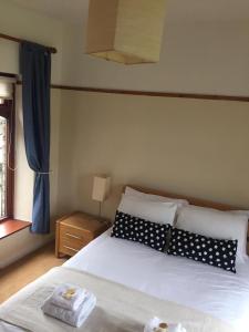 a bedroom with a bed with black and white pillows at Wicket Green Cottage in Hayfield