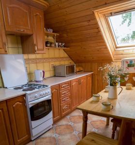 a kitchen with wooden cabinets and a stove and a table at Agroturystyka Lolkowo in Srokowo