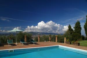 a swimming pool with two chairs and an umbrella at Agriturismo Villa Opera in Volterra