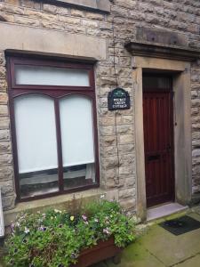 a stone building with a window and a door at Wicket Green Cottage in Hayfield