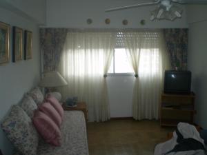 sala de estar con sofá, TV y ventana en Depto. 2 ambientes en Mar del Plata