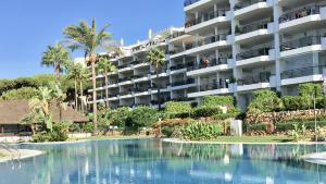a hotel with a swimming pool in front of a building at MI CAPRICHO C16 Beachfront Apartment in Mijas Costa