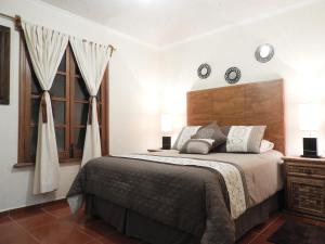 a bedroom with a large bed and two windows at Casa del Temezcuitate in Guanajuato