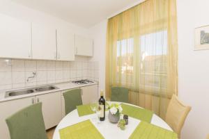 a kitchen with a table with a bottle of wine at Apartment Nediljka in Vodice