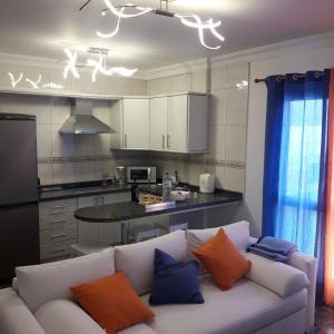 sala de estar con sofá blanco con almohadas de color naranja y azul en Vivienda FRALEMAR Arinaga., en Arinaga