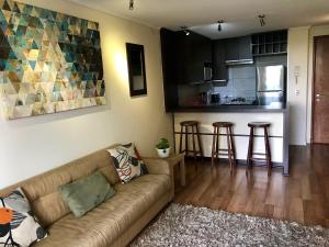 a living room with a couch and a kitchen at Mirando a Parque Arauco in Santiago