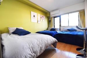two beds in a room with yellow walls at LIONS APARTMENT 516 in Tokyo