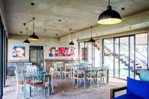 un comedor con mesas, sillas y ventanas en Lazy Koala en Hikkaduwa