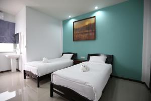 two beds in a room with a blue wall at SABUN-NGA HOSTEL in Chiang Rai