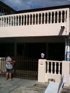 a woman standing in front of a building with a fence at Yong Homestay in Kuala Perlis