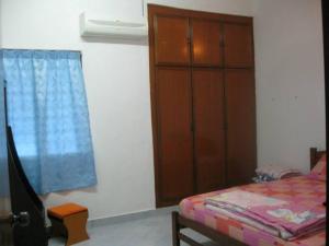 Yong Homestay في كوالا برليس: غرفة نوم بسرير وخزانة خشبية