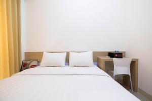 una camera da letto con un letto con 2 cuscini bianchi e una scrivania di Cozy Studio Tree Park Apt a Tangerang