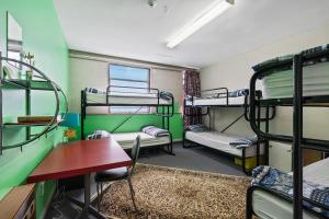 a room with three bunk beds and a table and chairs at Point Break Backpackers in Christchurch