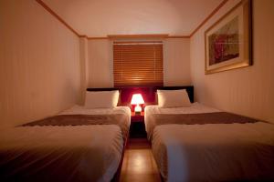 two beds in a small room with a lamp at Hotel Daewoo Inn in Seoul