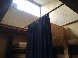 a room with a window and a bed with a curtain at Guest House Minato in Miyako