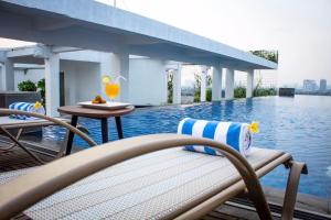 - une piscine avec des chaises et une table à côté de l'eau dans l'établissement Azana Suites Hotel Antasari, à Jakarta