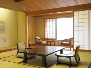 Habitación con mesa, sillas y ventana en Yugawara Onsen Kawasegien Isuzu Hotel, en Atami