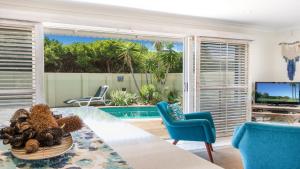 a living room with a table and chairs and a pool at Barefoot in Lennox- Beachfront Pool in Lennox Head