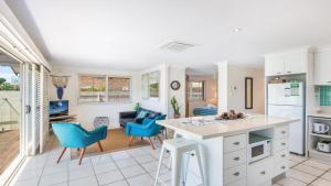 a kitchen and living room with a counter and chairs at Barefoot in Lennox- Beachfront Pool in Lennox Head
