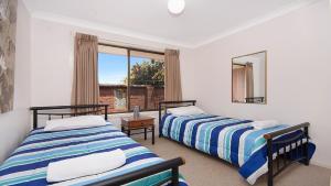 two beds in a room with a window at Alexander Palms in East Ballina