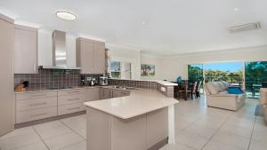 a kitchen with white cabinets and a living room at Surfside in East Ballina