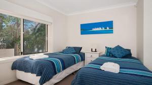 two beds in a bedroom with a window at Surfside in East Ballina +3 photos