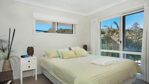 a white bedroom with a bed and a window at Surfside in East Ballina