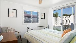 a white bedroom with a bed and a window at Betty's in Lennox Head