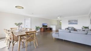 a dining room and living room with a table and a couch at Bailey's Beach House in East Ballina