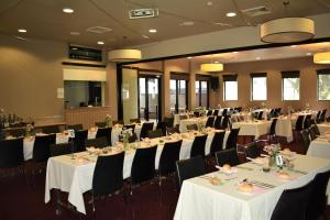 a banquet hall with white tables and black chairs at Best Western Blackbutt Inn in Newcastle