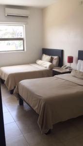 a room with two beds and a window at Suites Real Tabasco in Villahermosa