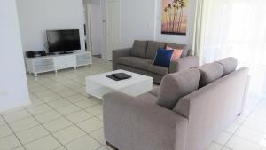 sala de estar con 2 sofás y TV en The Shores Holiday Apartments, en Mackay
