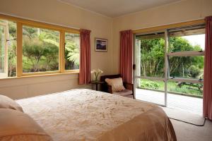 - une chambre avec un lit et une grande fenêtre dans l'établissement Te Hapu Coastal Cottages, à Collingwood